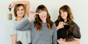 three women holding scissors and brush