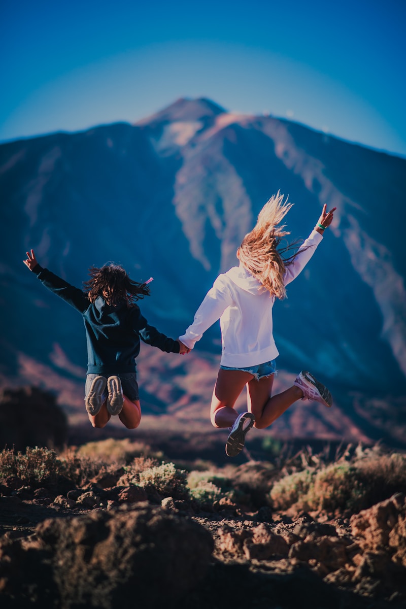 Photo by Fausto García-Menéndez woman in white shirt and black shorts jumping on brown grass field during daytime