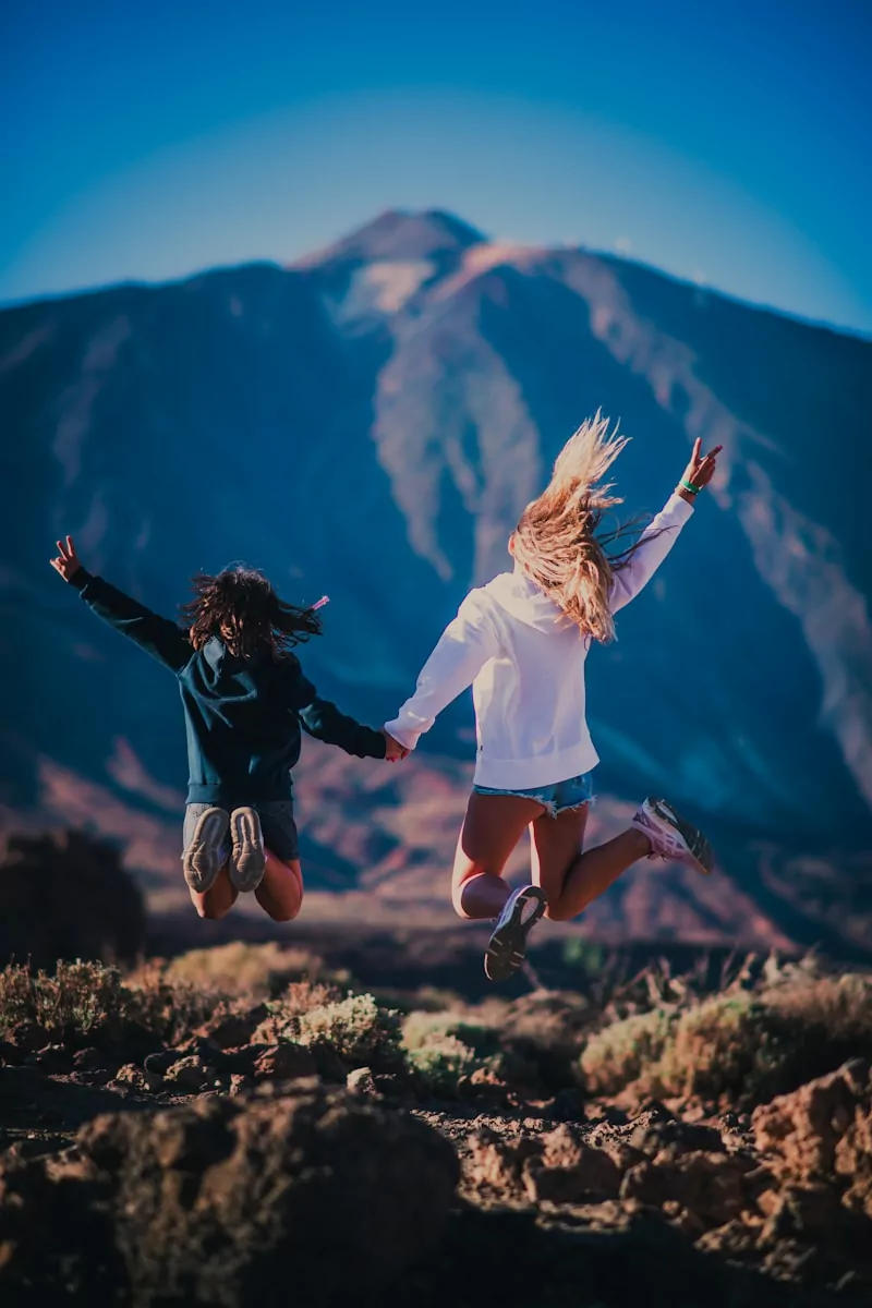 Photo by Fausto García-Menéndez woman in white shirt and black shorts jumping on brown grass field during daytime
